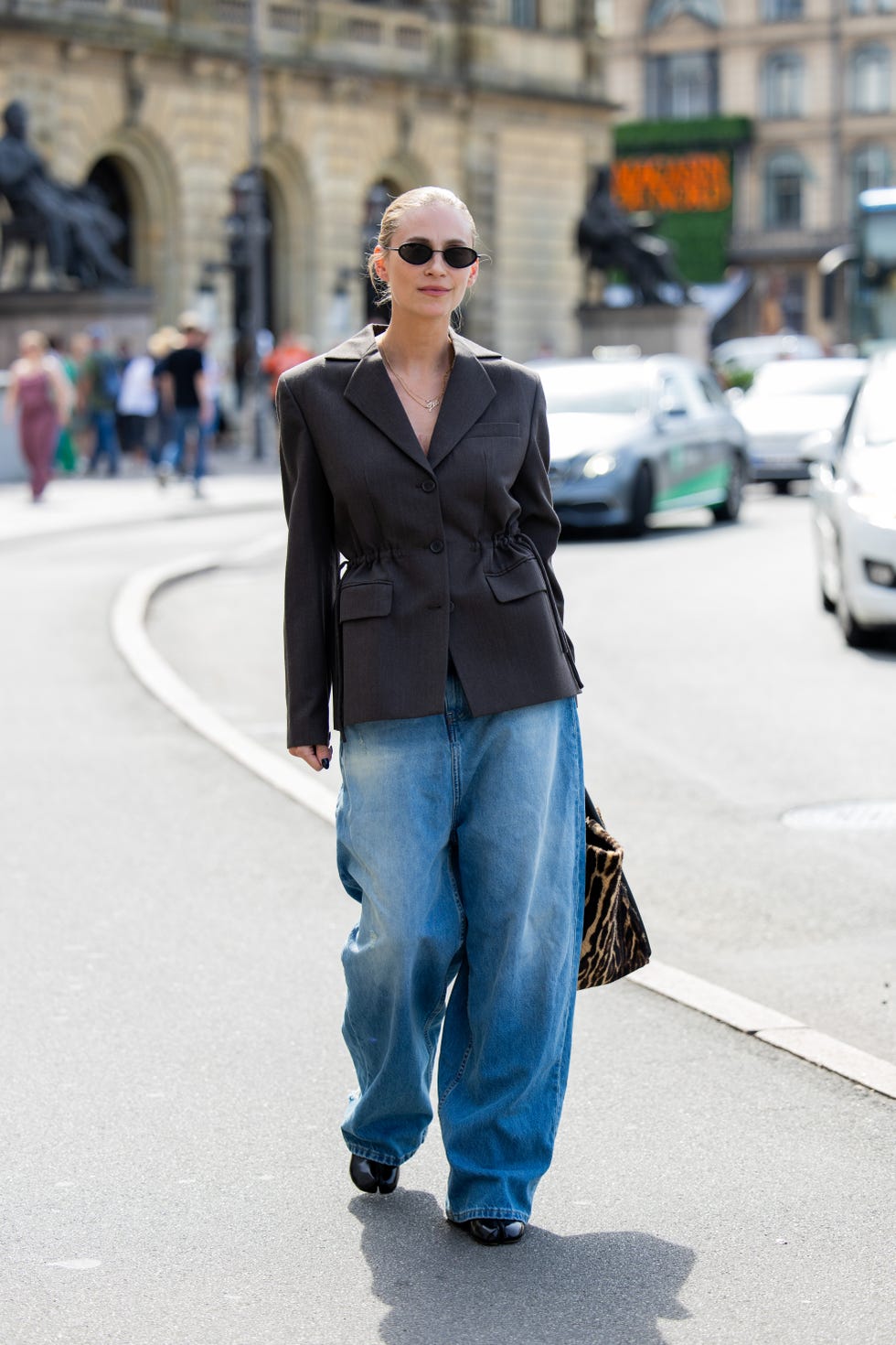 a model wears a waisted blazer and wide leg jeans in copenhagen