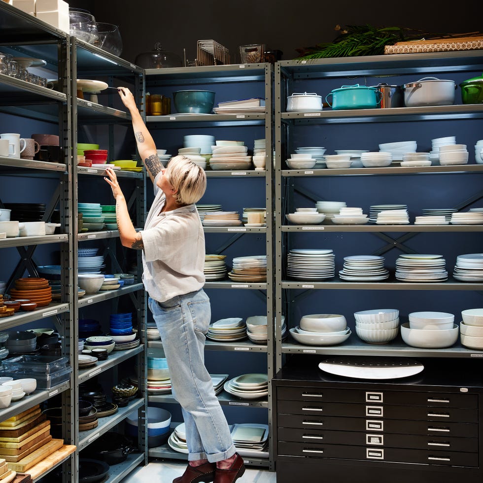 A woman taking a plate from a shelf