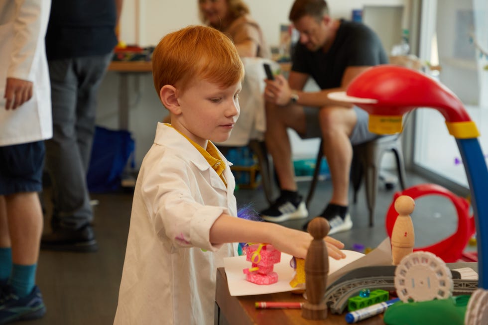 a kid sits at an art table, working with clay
