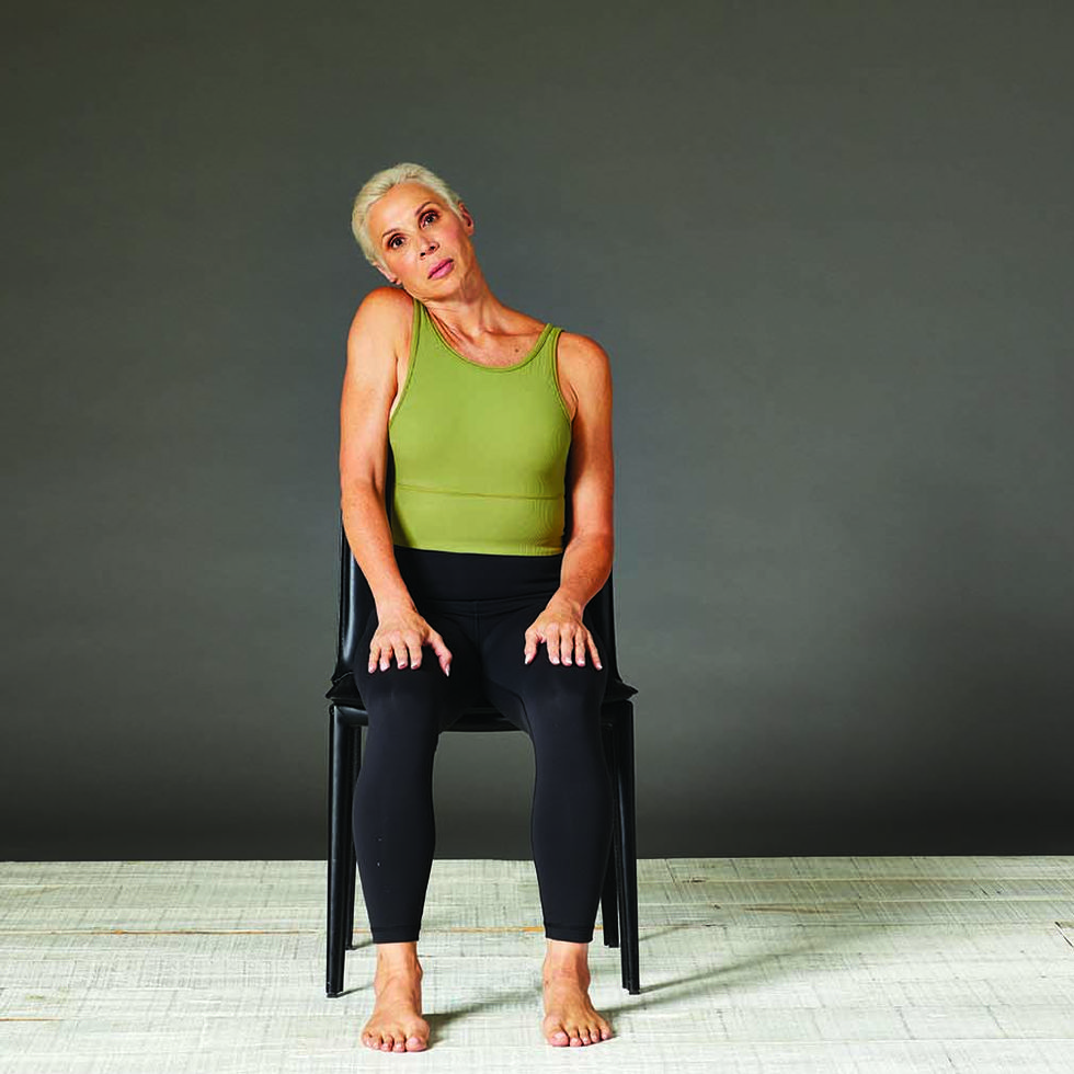 woman doing an ear and shoulder tap stretch in a chair