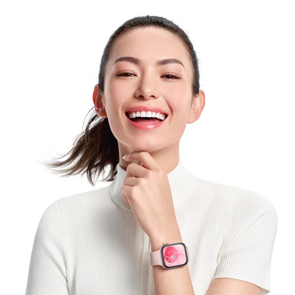 a woman smiling with her hand on her chin, wearing a smartwatch
