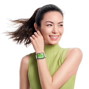 a smiling woman wearing a green pleated vest with a matching green smart watch on her wrist