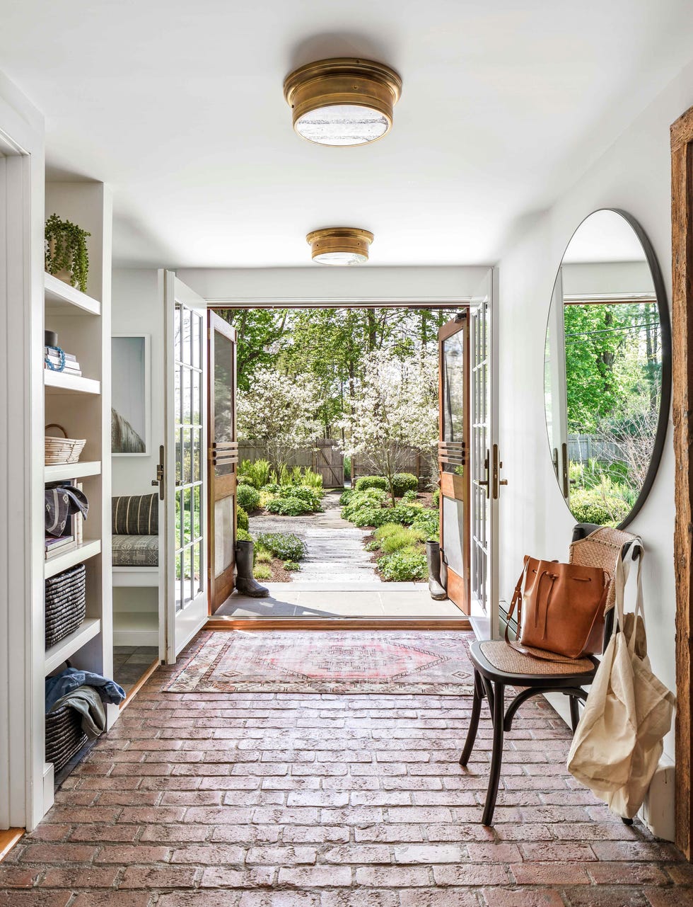 a wide entry in a converted dairy barn that has opened screen doors and brick floors