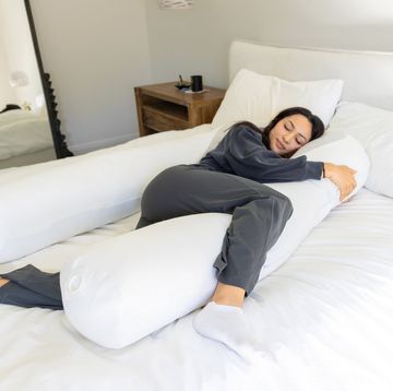 woman lying on u shaped pillow in bed
