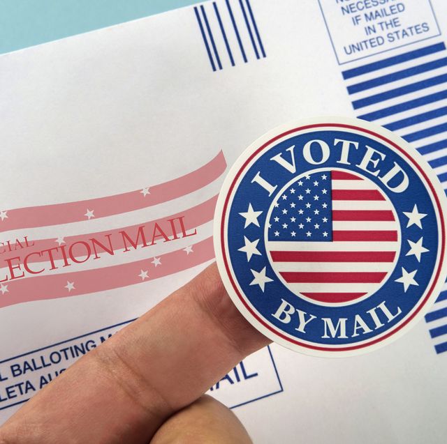 human finger holding sticker above voting mail