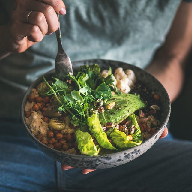 Vrouw eet hummus bowl met avocado