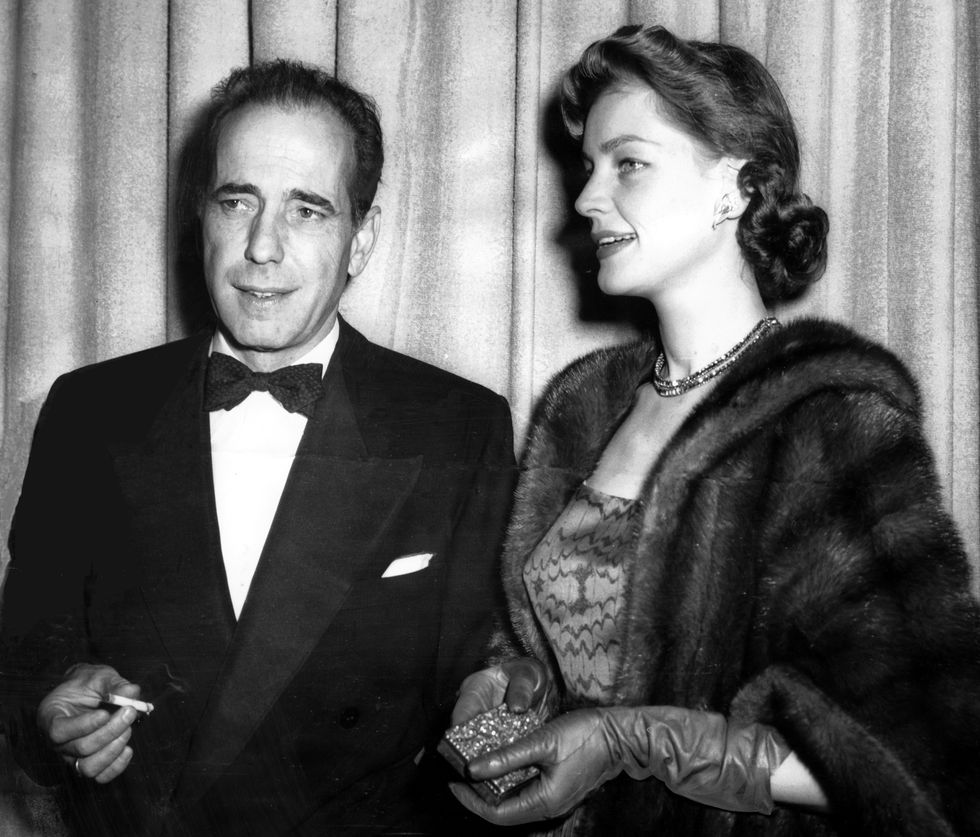 humphrey bogart and his film star wife lauren bacall pause for a smoke as they arrived at the theate