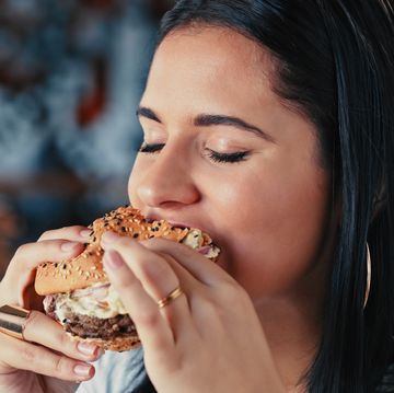 shot of a young woman enjoying a delicious burger at a restaurant