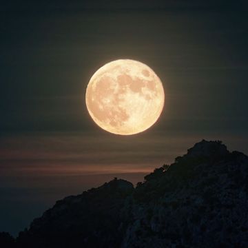 a mountain with a full hunter's moon in the background