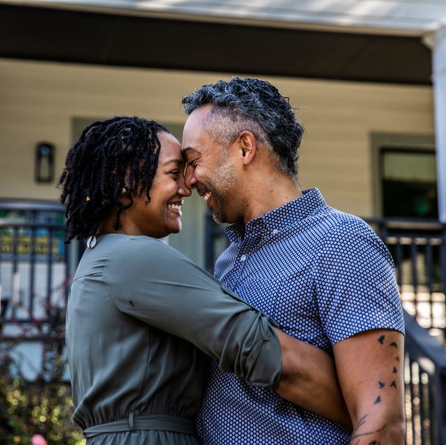 husband and wife embracing in front of new home