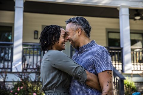 husband and wife embracing in front of new home
