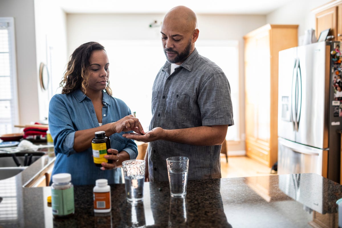 husband and wife taking vitamins at home