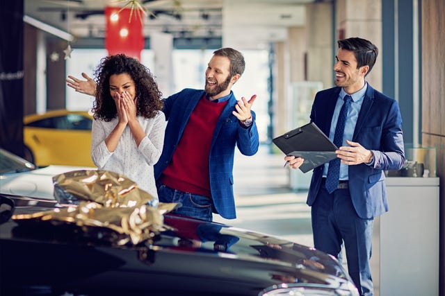 husband is surprising his wife with a new car