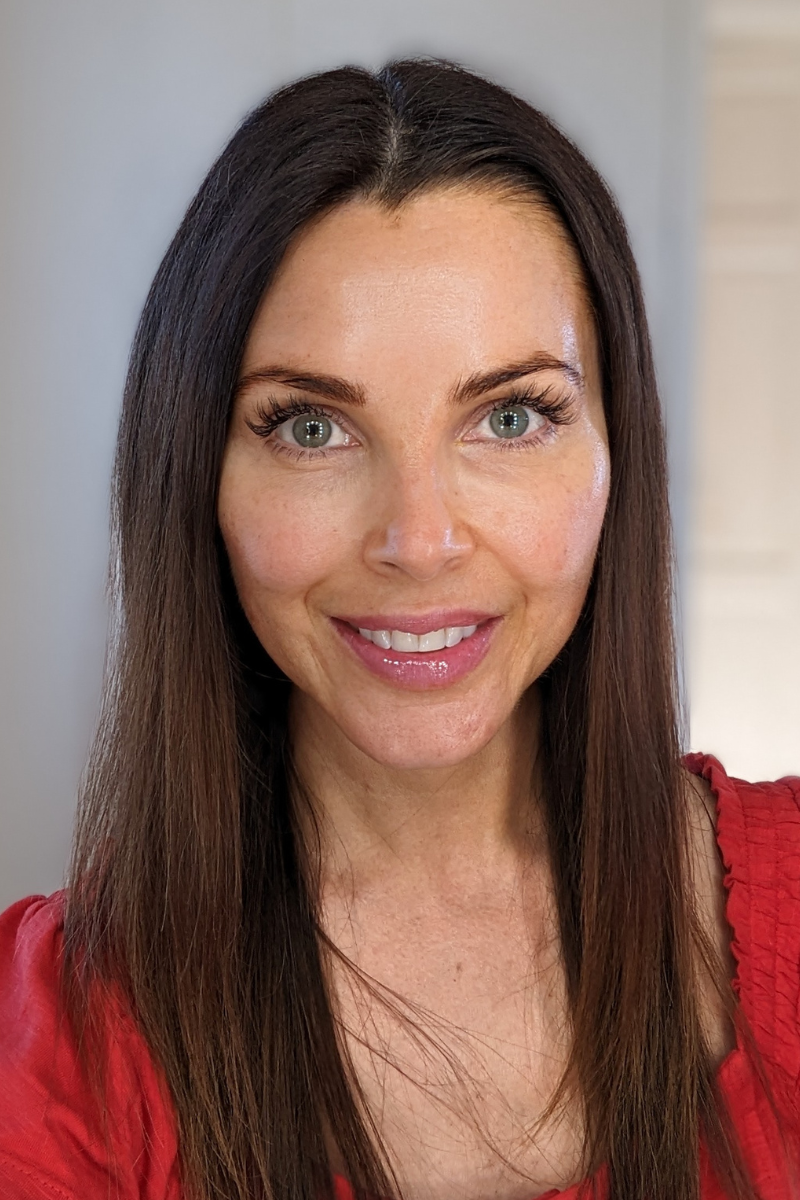 a closeup portrait of a person with long brown hair wearing a red top
