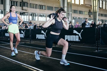 a woman doing a lunge with a sandbag in a fitness competition