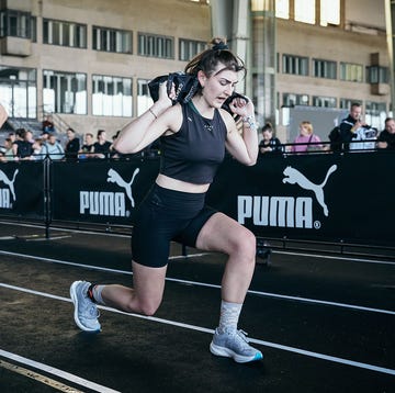 a woman doing a lunge with a sandbag in a fitness competition a woman doing a lunge with a sandbag in a fitness competition
