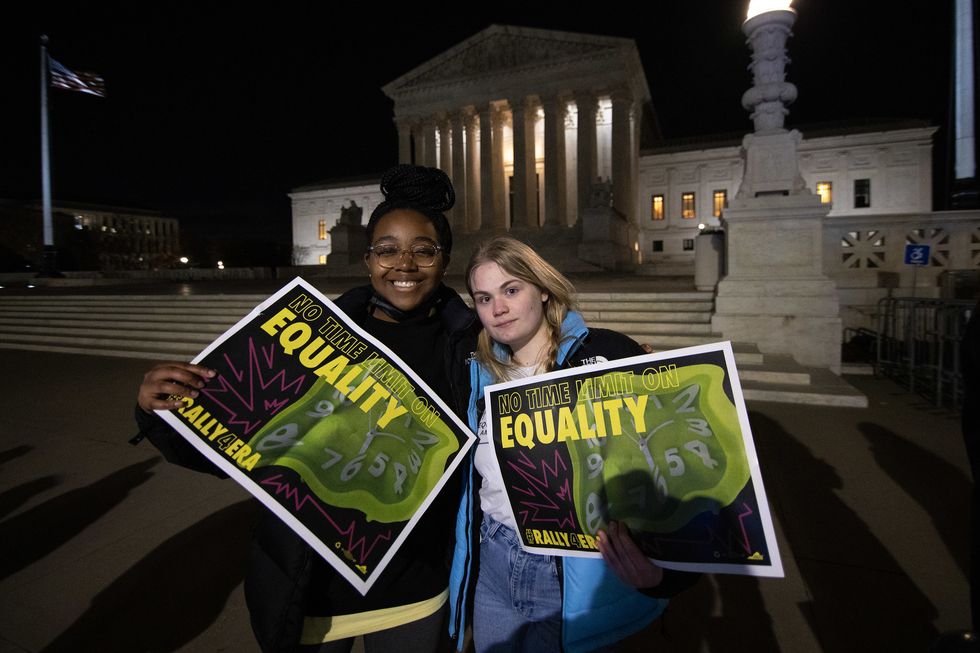 two organizers holding signs that read no time limit on equality