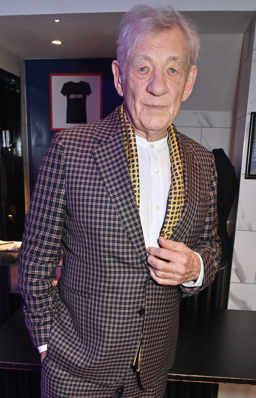 sir ian mckellen in a checkered pattern suit as he goes to collect the special recognition award at the pantomime awards 2023