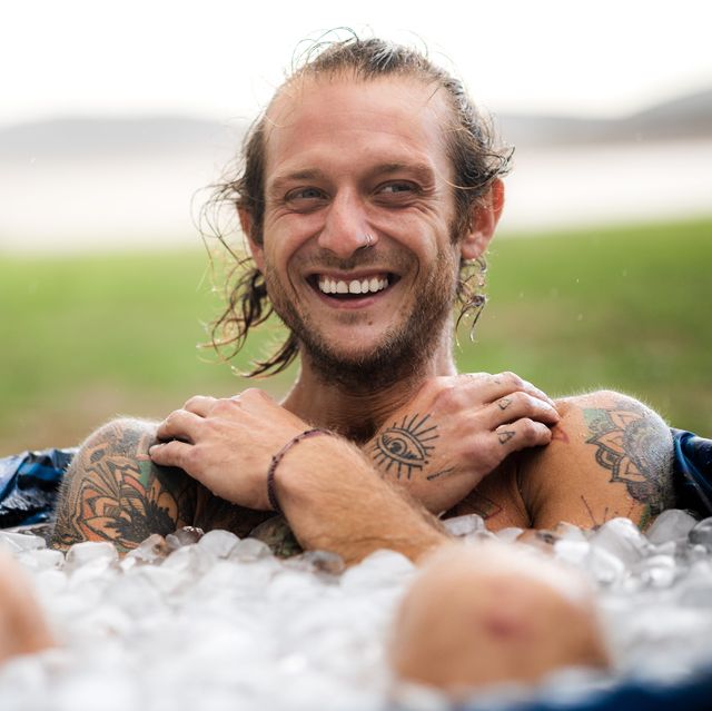 smiling blond man taking an ice bath in the middle of a field