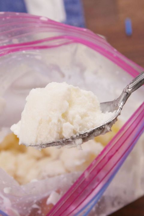 a spoon full of homemade ice cream comes out of a ziploc bag filled with more ice cream as part of this at home science experiment for kids