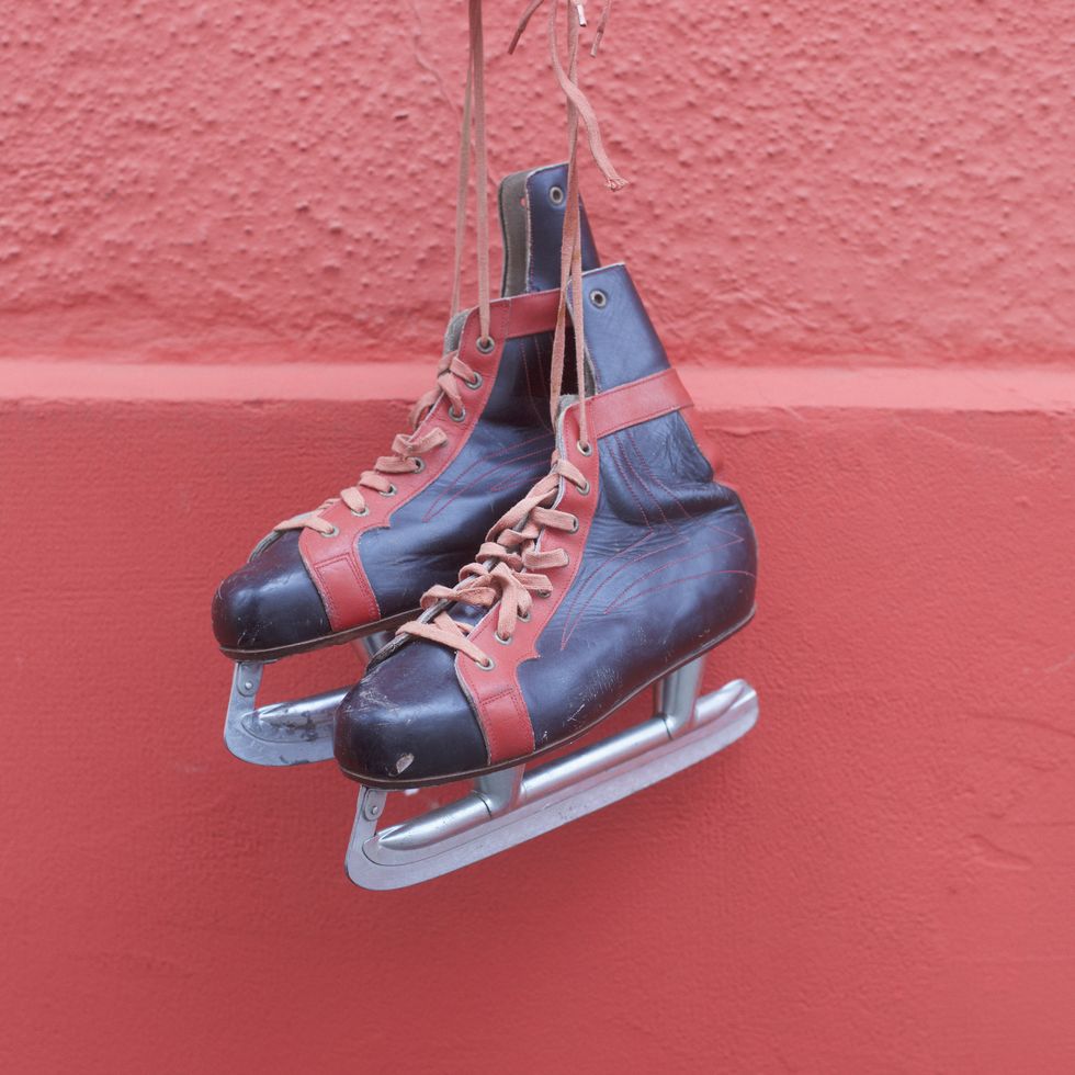 Ice skates hanging against red wall