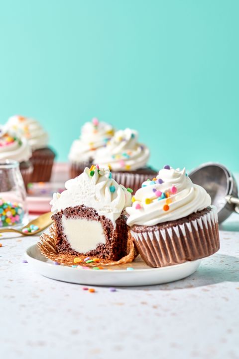 ice cream stuffed chocolate cupcakes with white frosting and rainbow sprinkles on top