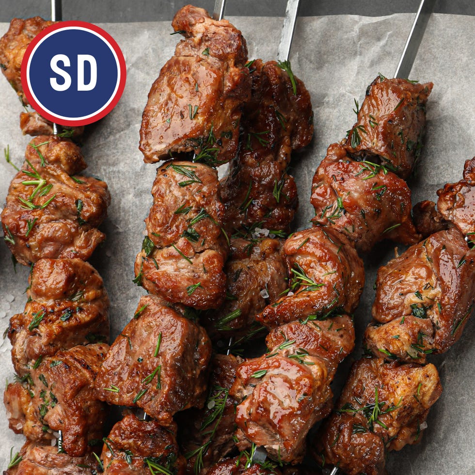 grilled meat skewers garnished with herbs on a serving surface