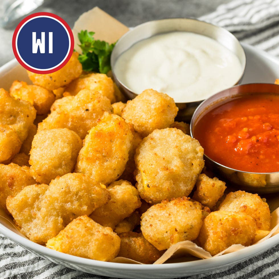 a bowl of goldenbrown cheese curds served with two dipping sauces