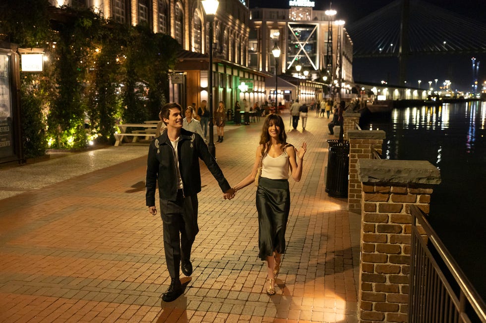 Couple walking handinhand along a waterfront pathway at night