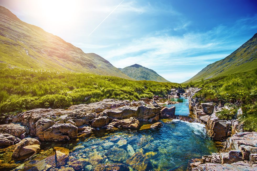 idyllic scene with mountains and stream in scottish highlands near glen coe