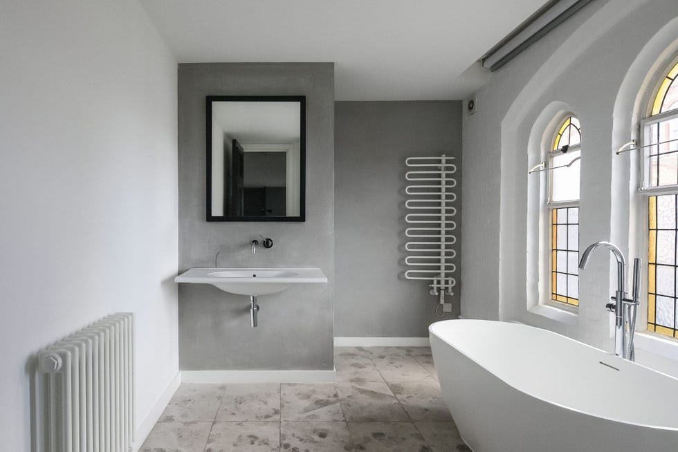 baño decorado en tonos grises con bañera exenta blanca y vidrieras