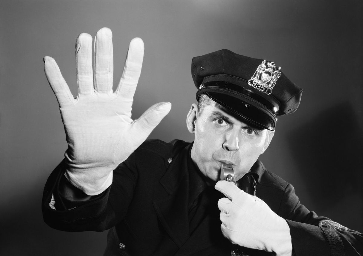 1950s 1960s police man looking at camera hat with badge blowing whistle white gloved hand up to halt stop traffic  photo by h armstrong robertsclassicstockgetty images