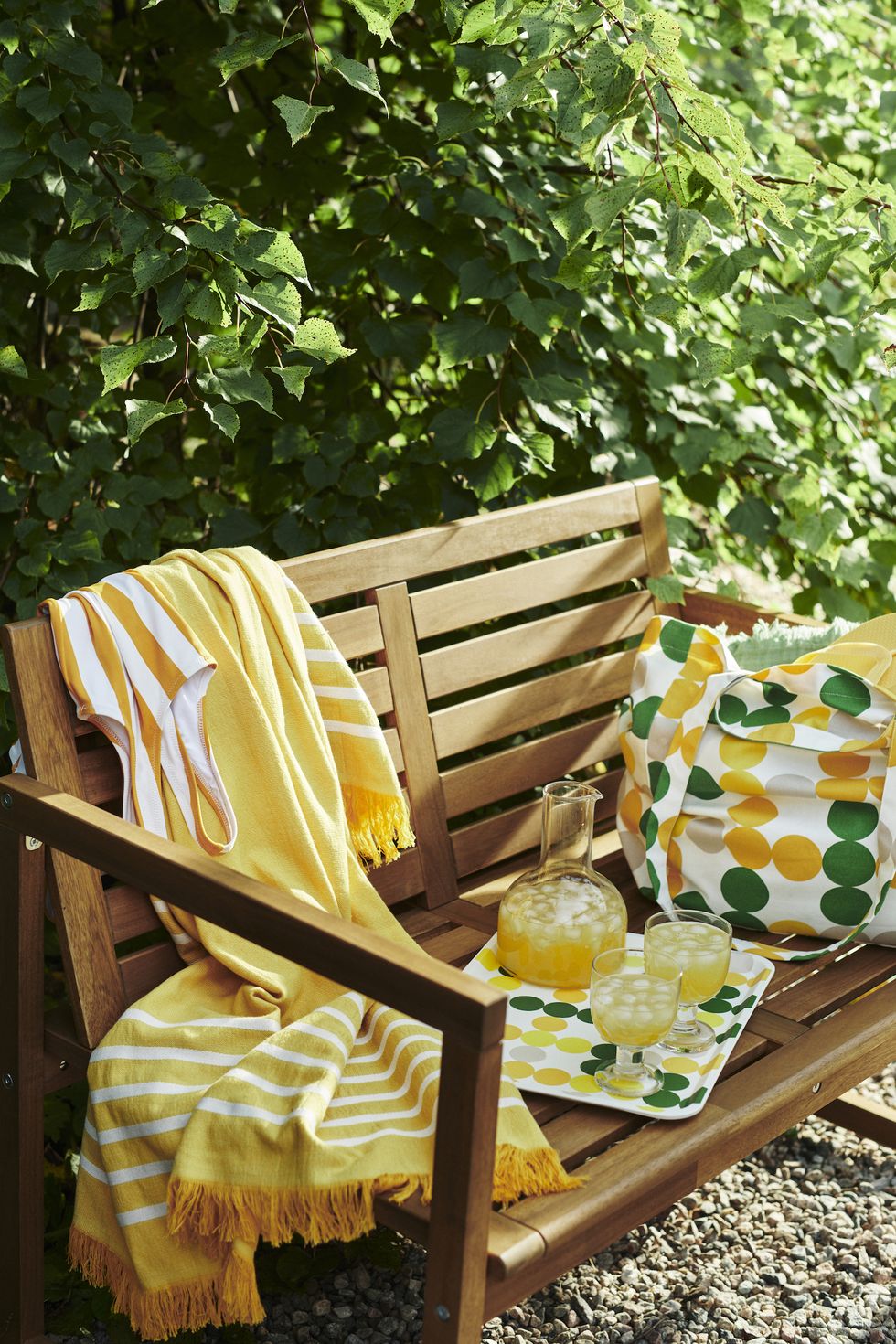 outdoor bench with yellow throw and glasses of drink