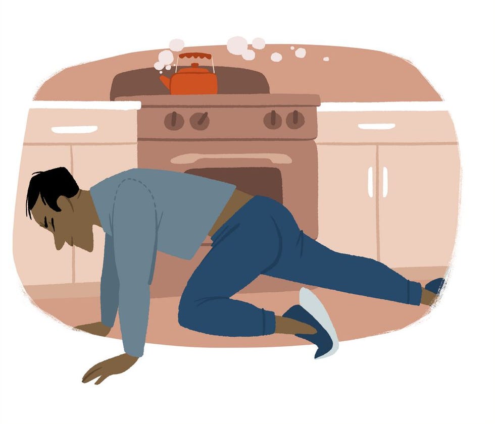 a man on the floor reaching towards a stove with a kettle boiling