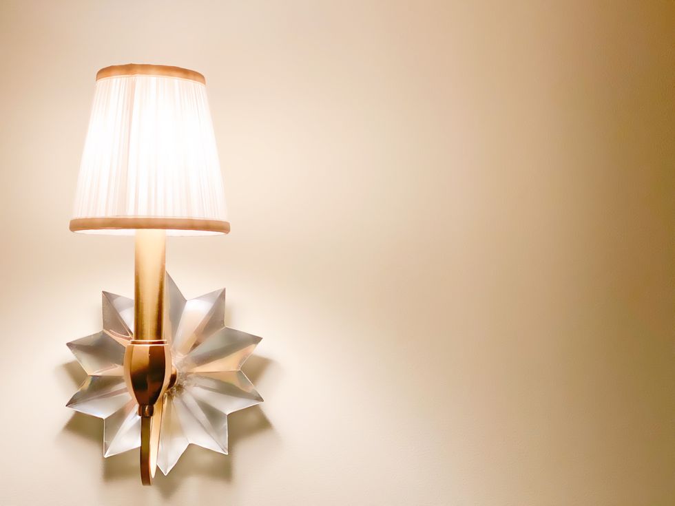illuminated brass wall sconce with decorative multipoint crystal star base in bedroom