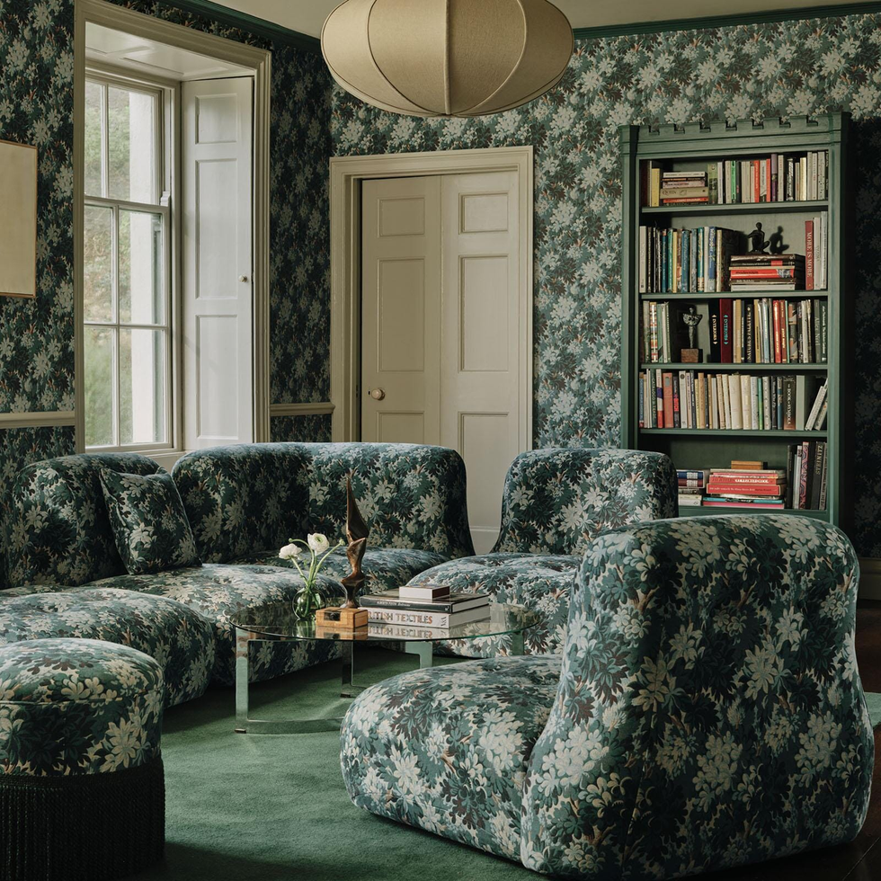 a room full of green patterned wallpaper and sofas and seats in the same pattern