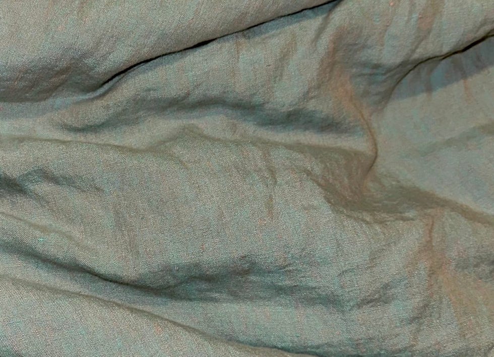 a close up of the texture of some light green and tan linen bedding from linoto
