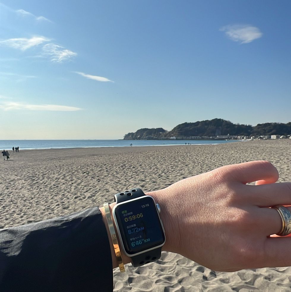 a hand holding a watch on a beach