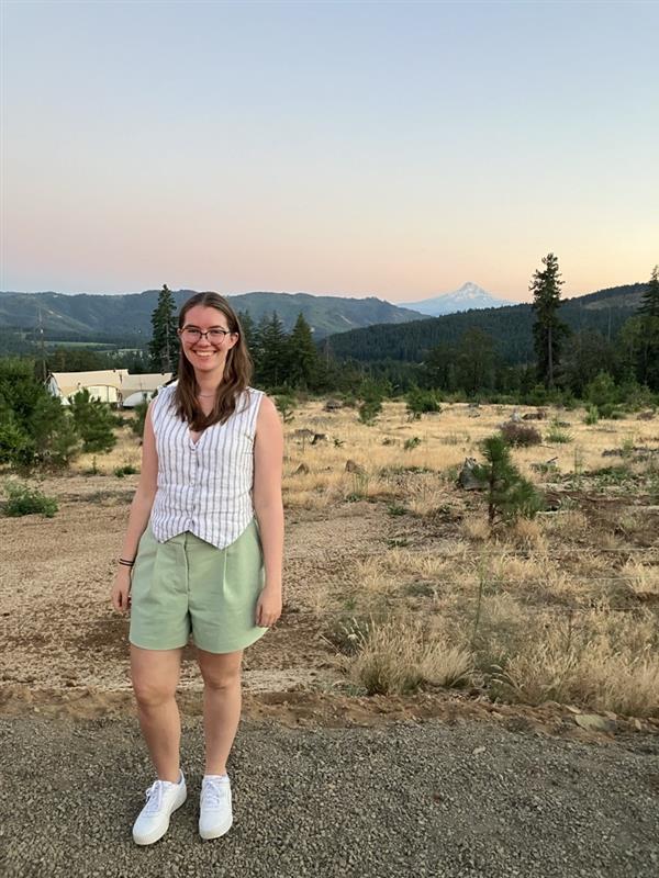 person stands in front of scenic outdoor setting