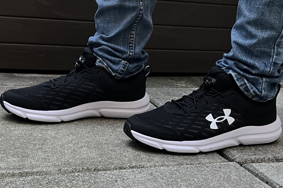 a tester wearing pair of black and white under armour charged asset 10 sneakers as part of good housekeeping's testing for the best walking shoes for men