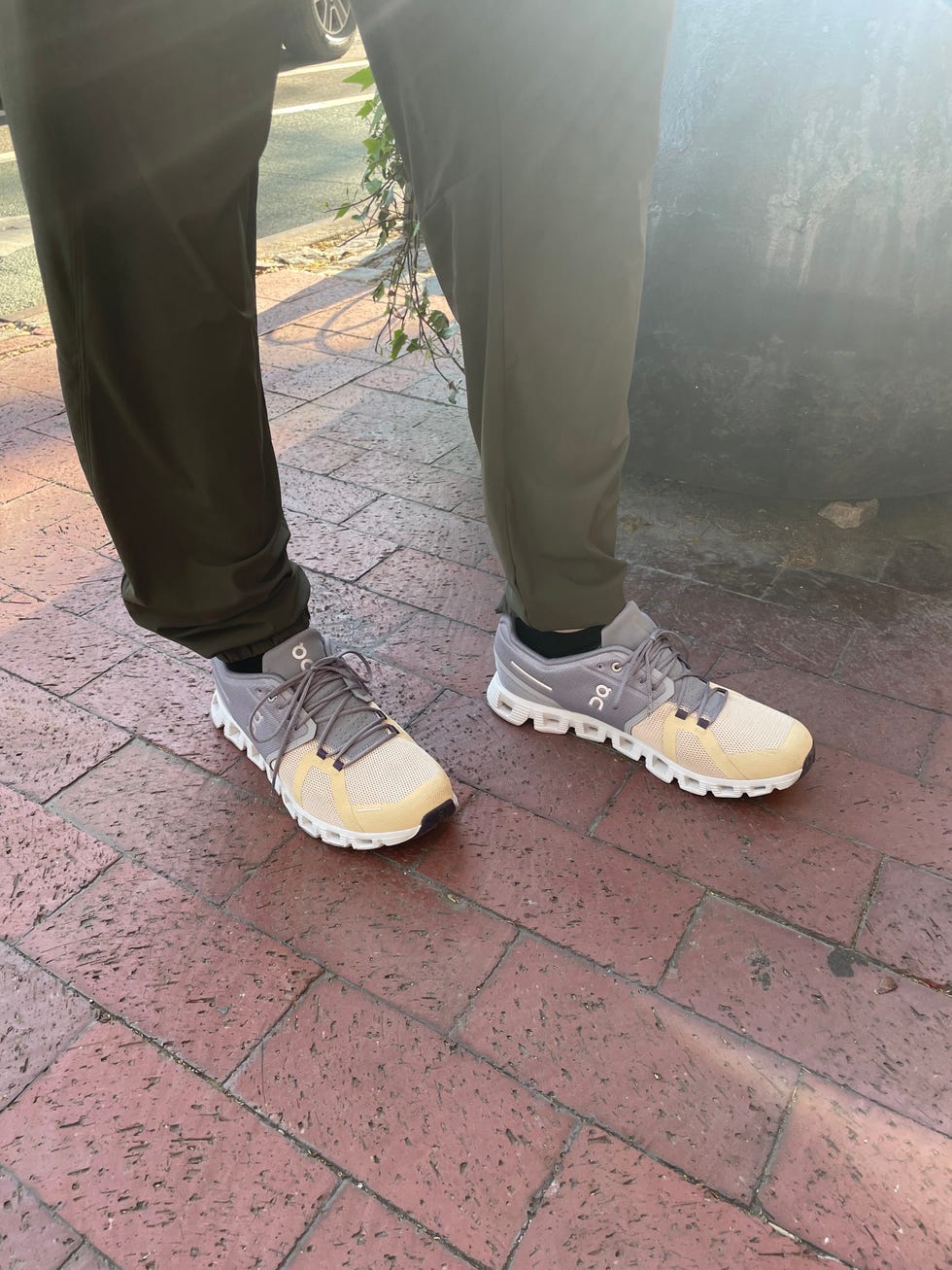 a person wearing slip on cloud 5 sneakers in grey and yellow