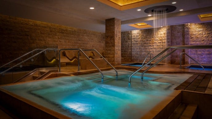 indoor spa area featuring a heated pool and calming lighting