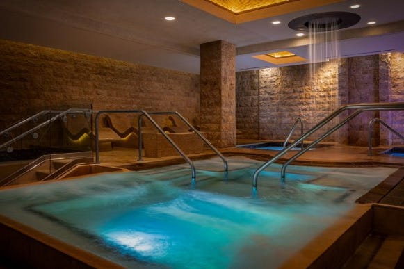 indoor spa area featuring a heated pool and calming lighting indoor spa area featuring a heated pool and calming lighting