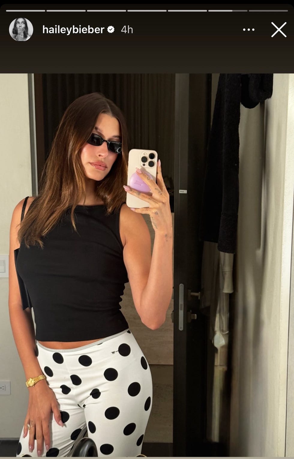 a person posing for a mirror selfie wearing a black top and white pants with black polka dots