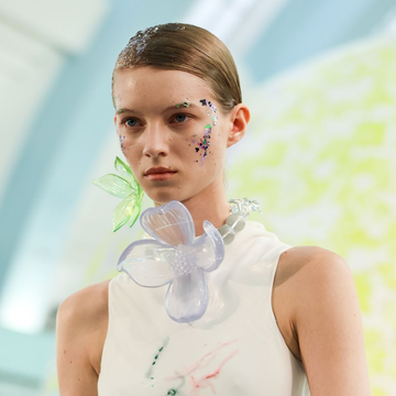 a model wears gigantic floral jewelry at a runway show