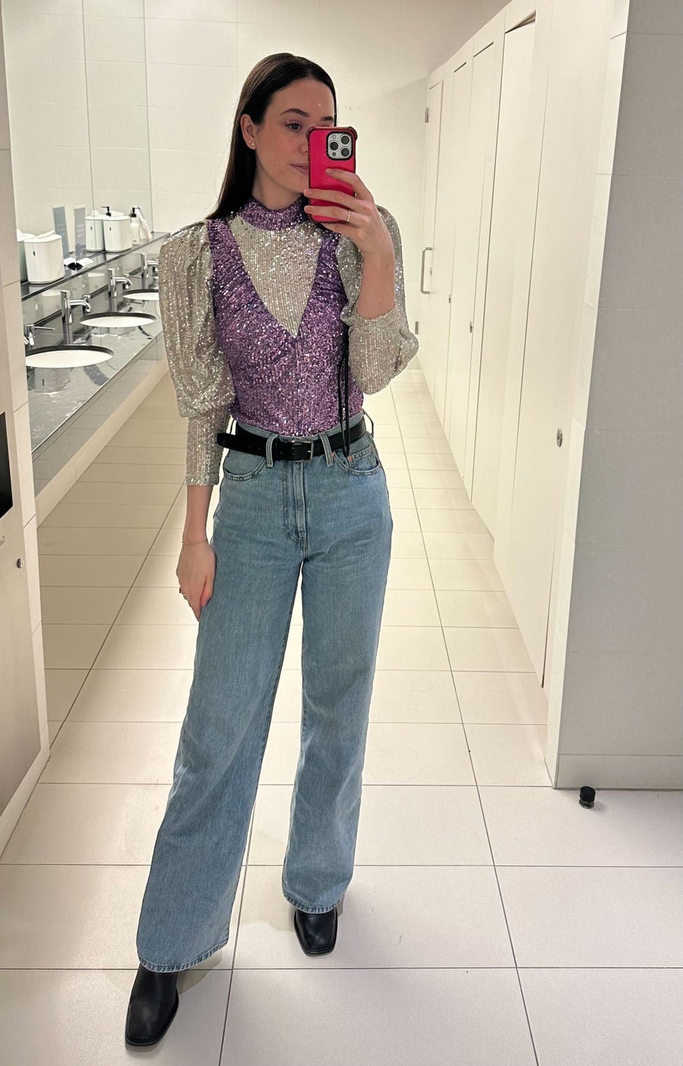 a tester wearing light blue levi's ribcage wide leg women's jeans with a sequin top and black boots in a mirror selfie, good housekeeping's best jeans for women