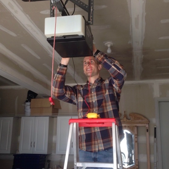a man standing on a ladder installing a garage door opener