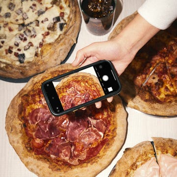 persona sujetando un telefono sobre pizzas