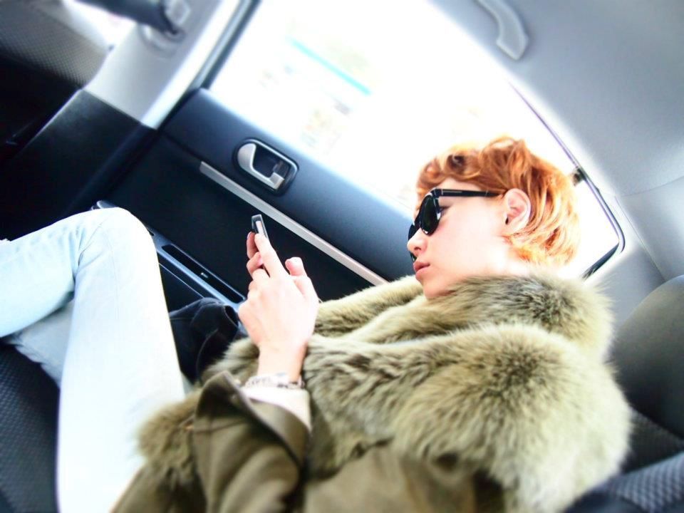 a person in a fur coat and sunglasses holding a cell phone