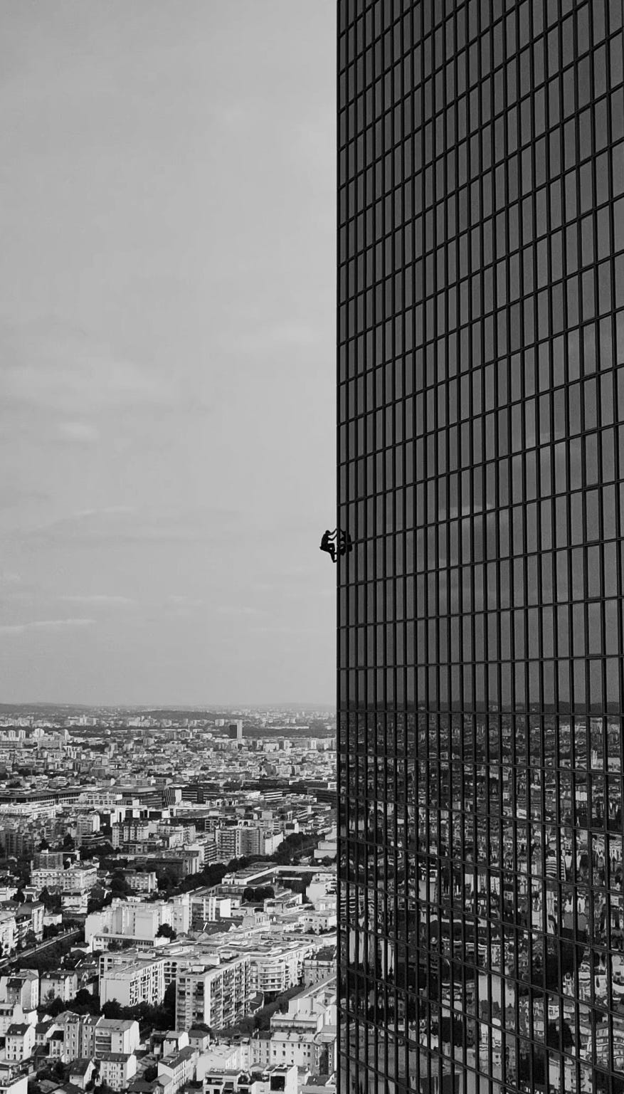 person scaling the side of a tall building in an urban setting